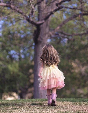 menina no jardim que caminha para uma árvore